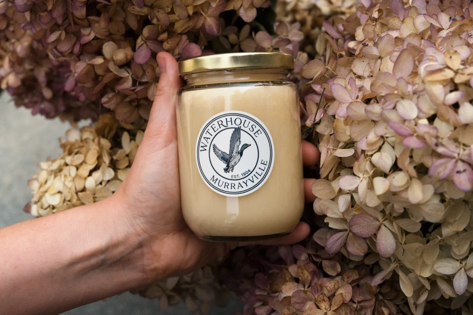 A jar of wildflower honey held in the garden at Waterhouse Farm
