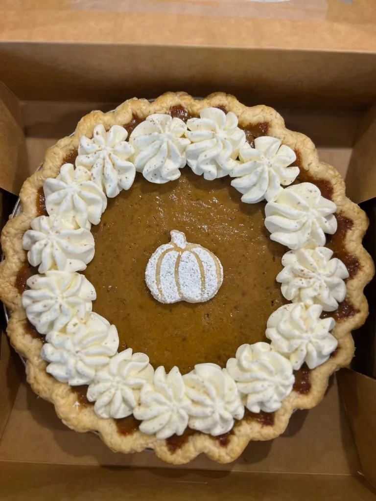 Pumpkin pie with whipped cream and a sugar pumpkin on top