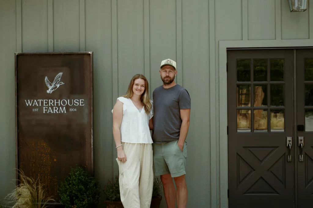 Two people at the Waterhouse Farm store in Murrayville, beside the farm sign