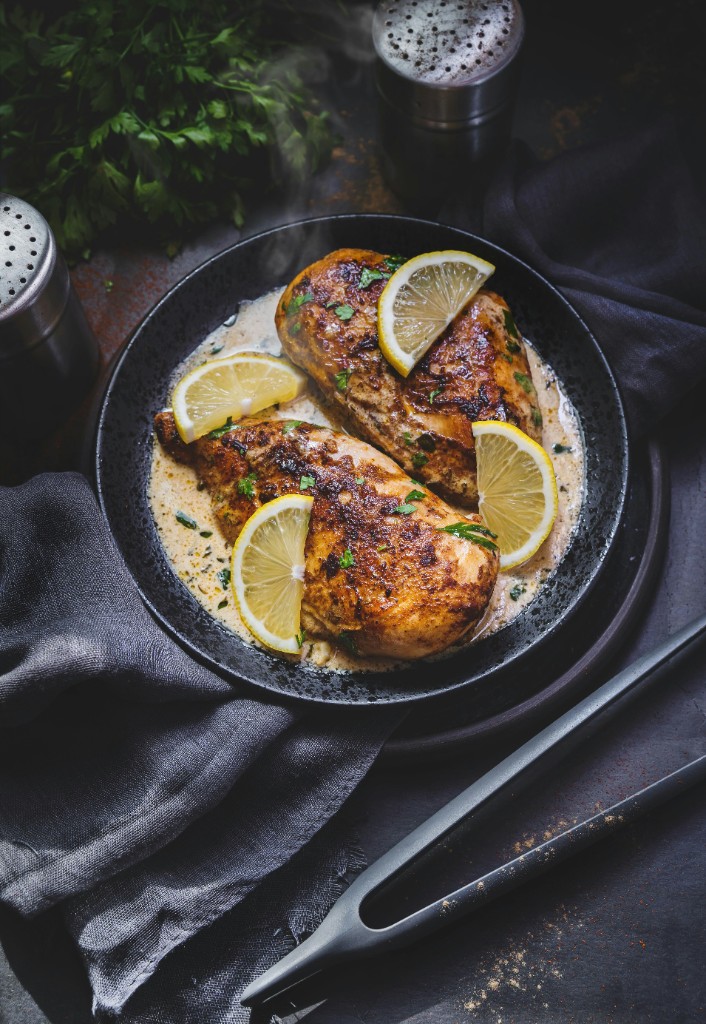 Pan seared chicken breasts in creamy lemon herb sauce with lemon slices and parsley